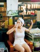 A woman sitting in a chair drinking from a cup.