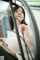 A woman in a white dress is standing behind a metal railing.