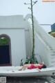 A woman laying on top of a bathtub next to a plant.