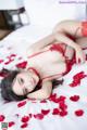 A woman laying on a bed covered in rose petals.