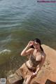 A woman in a leopard print bikini standing on a rock by the water.