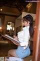 A woman sitting on a table writing on a clipboard.