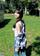 A woman standing in a grassy field next to a trailer.