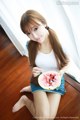 A woman sitting on the floor eating a slice of watermelon.