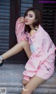 a woman sitting on the steps of a building wearing a pink jacket