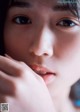 A close up of a woman's face with her hand on her chin.