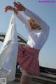 A woman in a white shirt and pink skirt holding a white sheet.