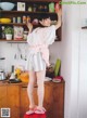 A woman standing on top of a red stool in a kitchen.