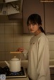 A woman standing in a kitchen holding a kettle.